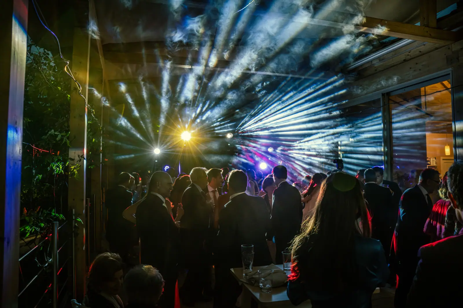 Cabina de DJ iluminada en la noche, equipamiento de sonido profesional con público celebrando.