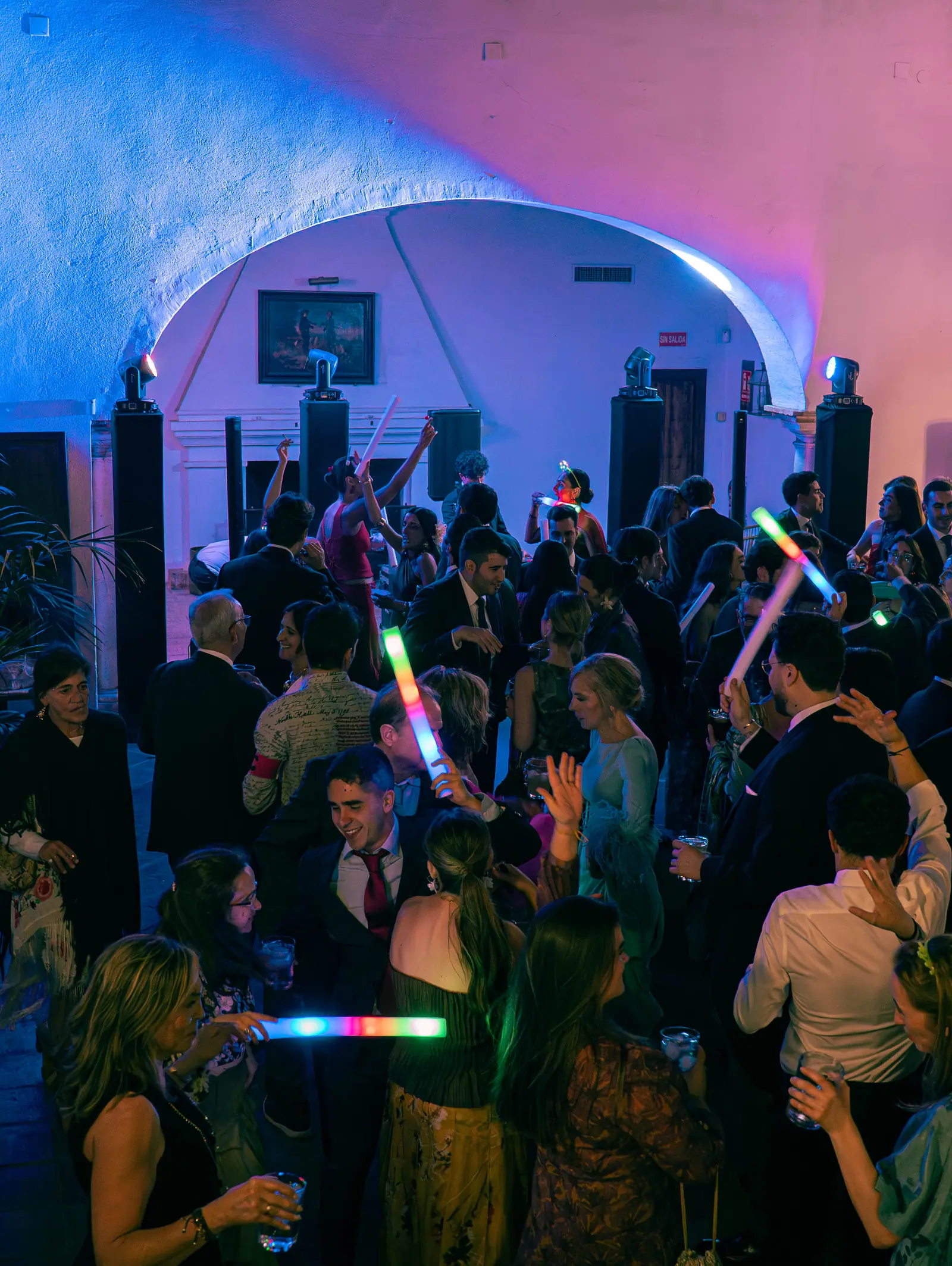 Cabina de DJ bajo arco arquitectónico con montaje de luces LED y pista de baile con invitados