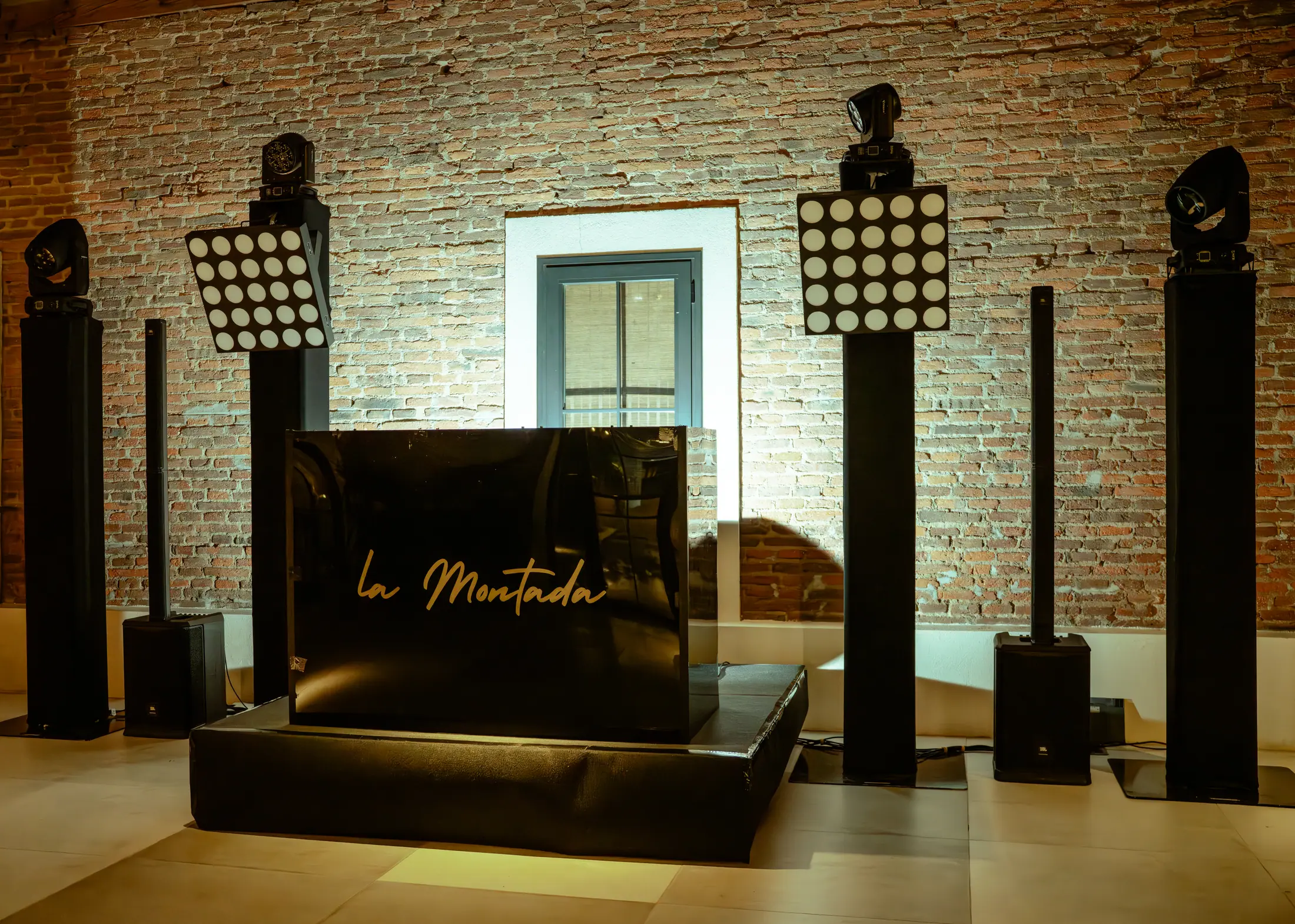 Entrada del evento con iluminación arquitectónica sobre una pared de ladrillo