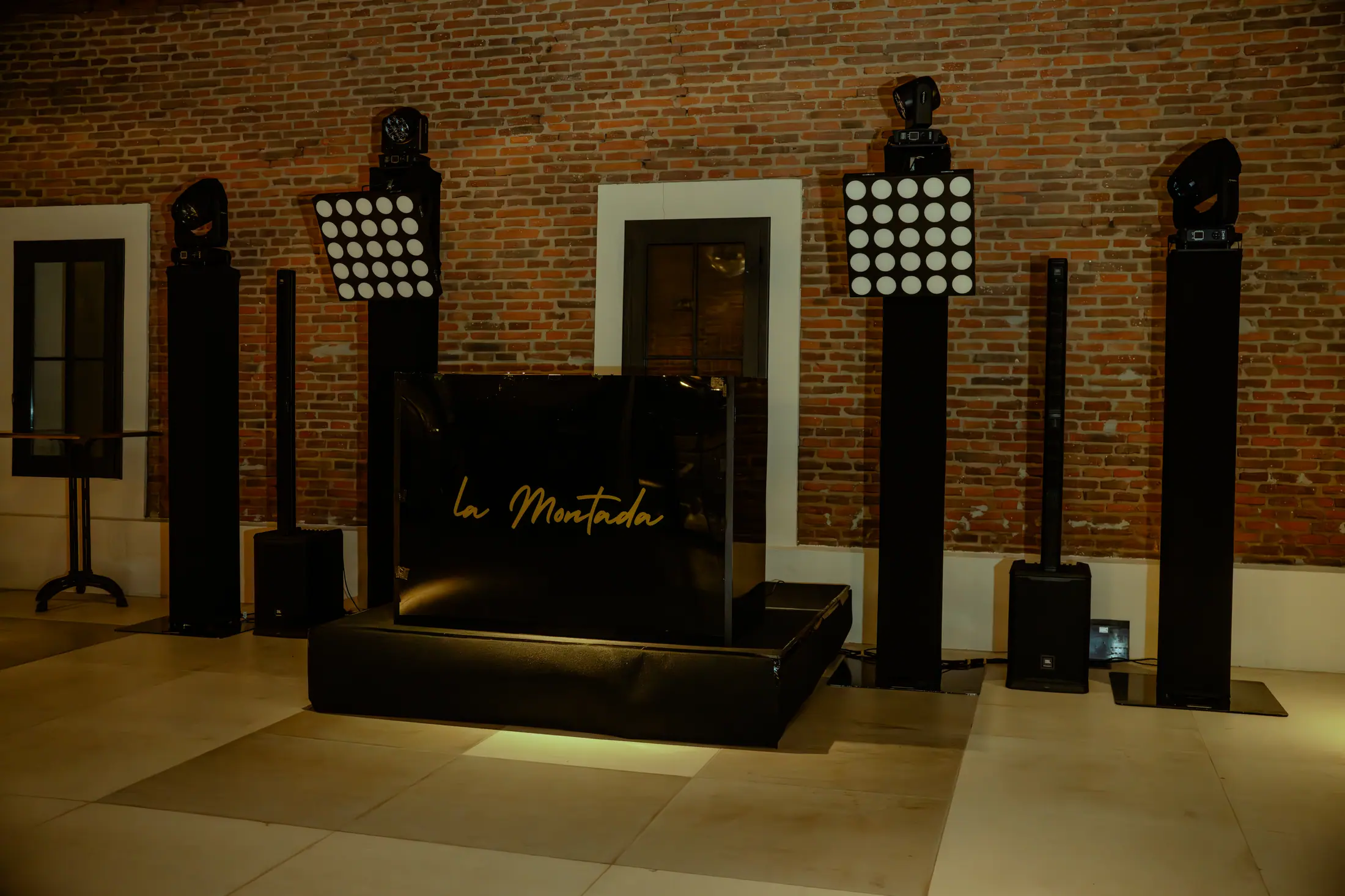 Sala de eventos amplia con estructura negra e iluminación dorada