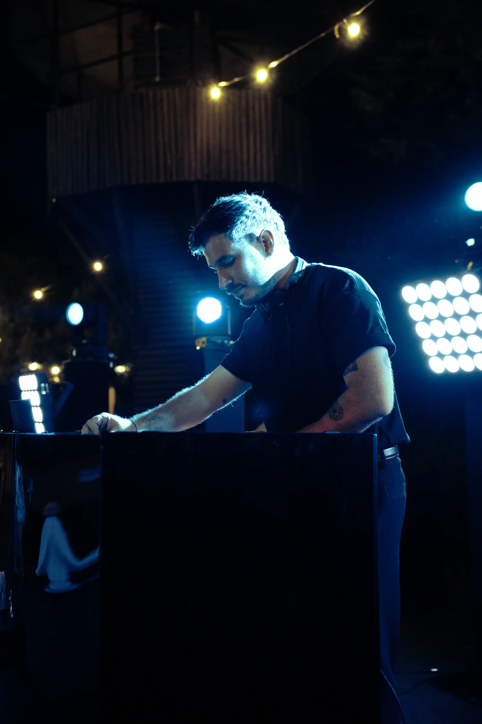 DJ en consola iluminada en azul, trabajo de producción y sonido