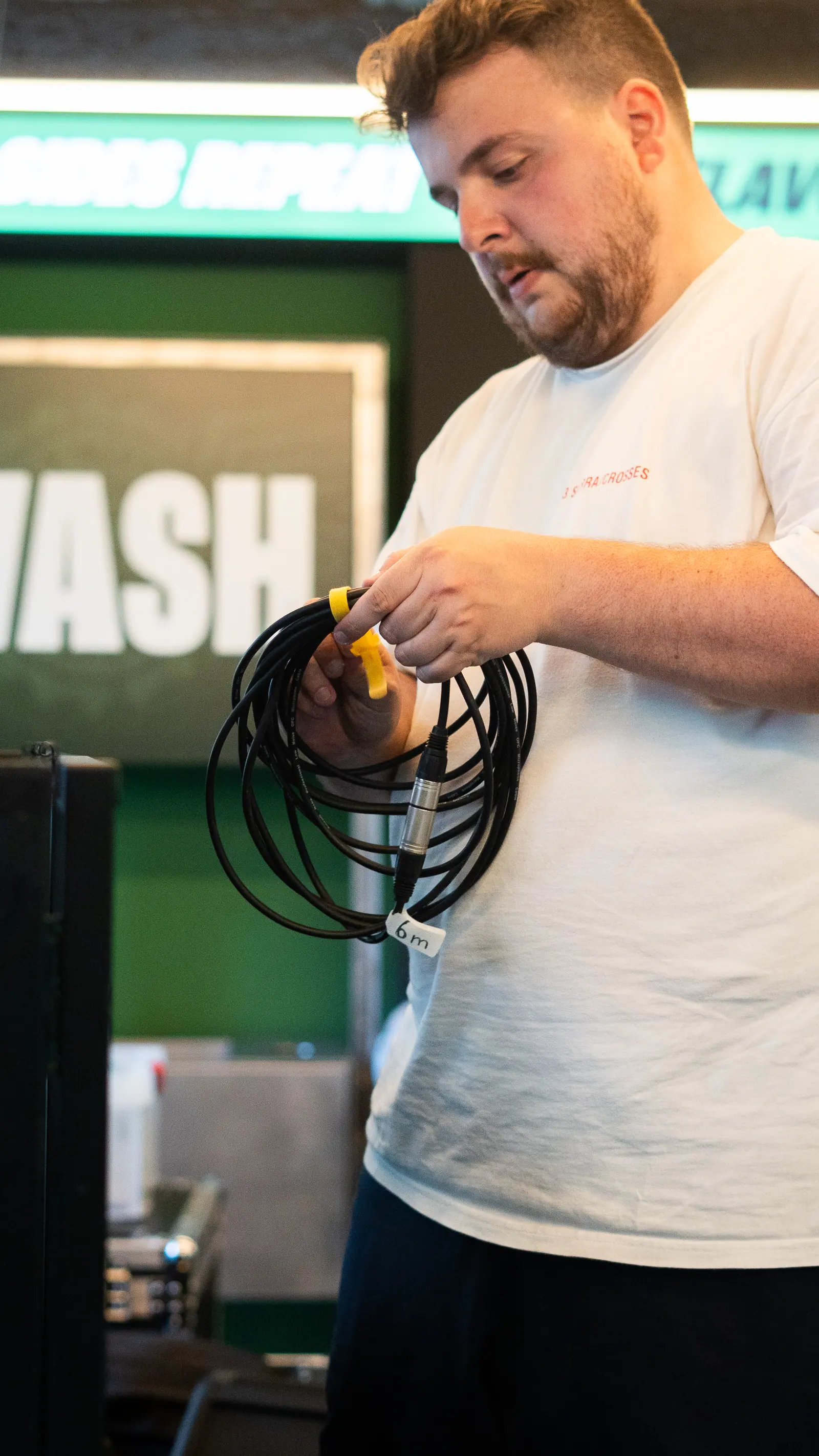 Técnico operando en escenario profesional con estructura verde de marca al fondo