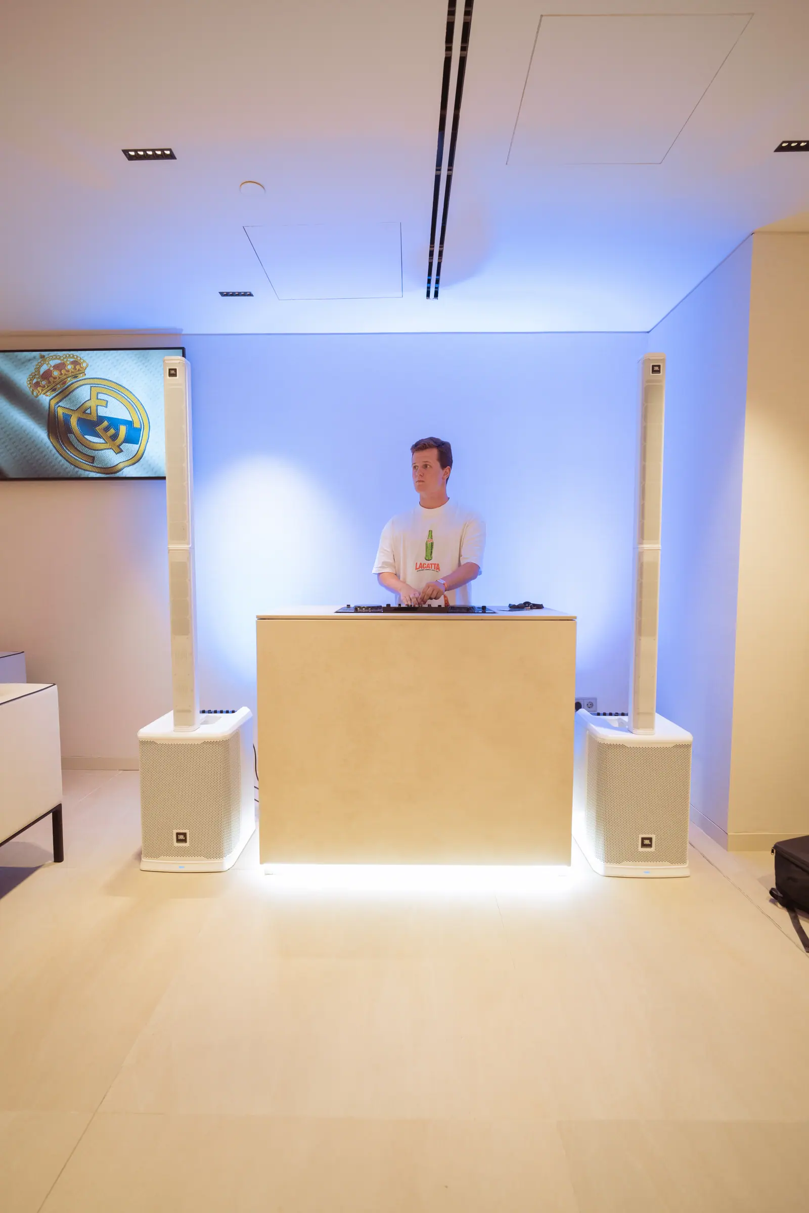 Cabina de DJ minimalista con arquitectura de piedra crema y pared iluminada