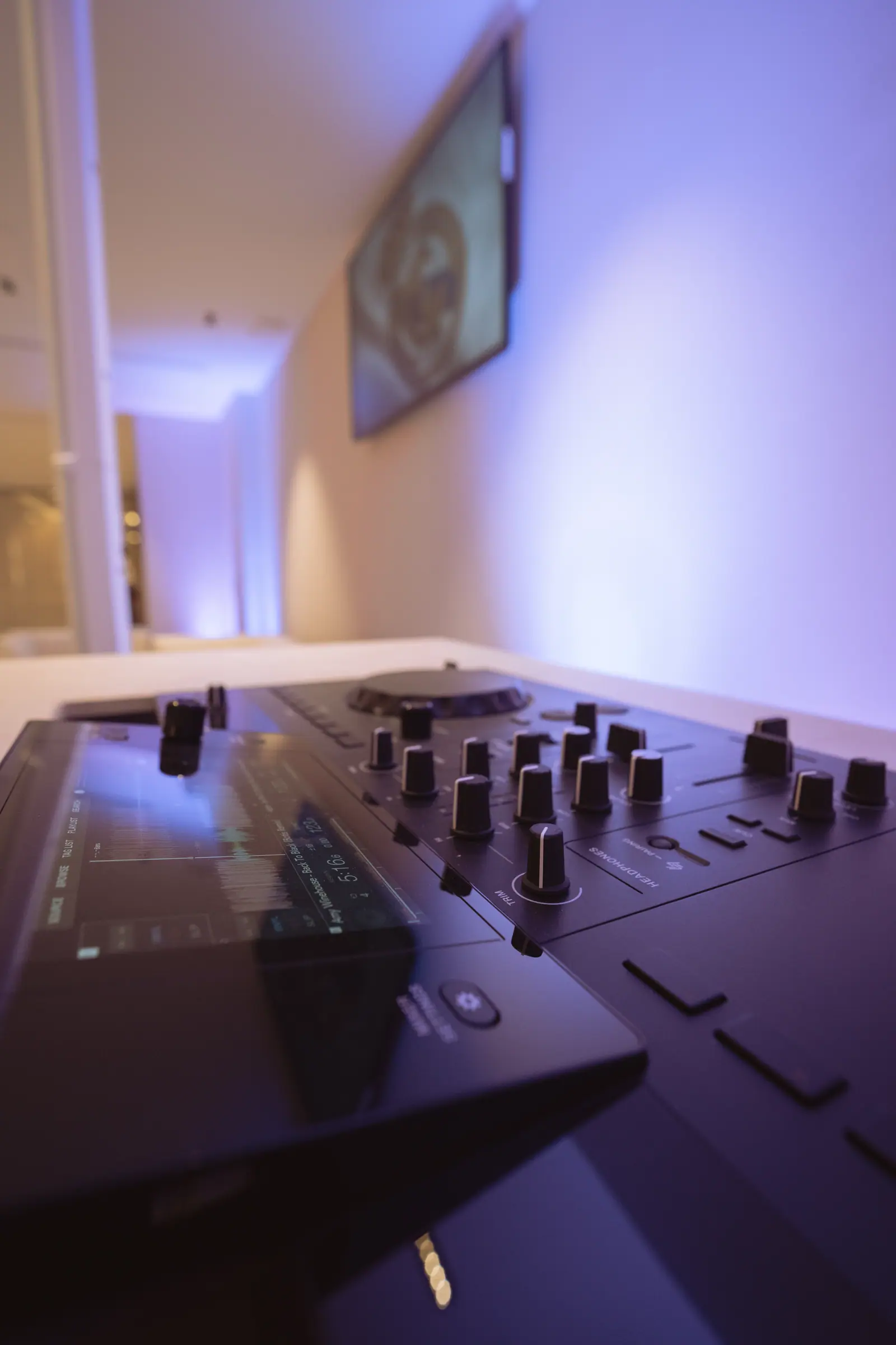 Consola de DJ profesional bajo iluminación morada y azul en montaje audiovisual