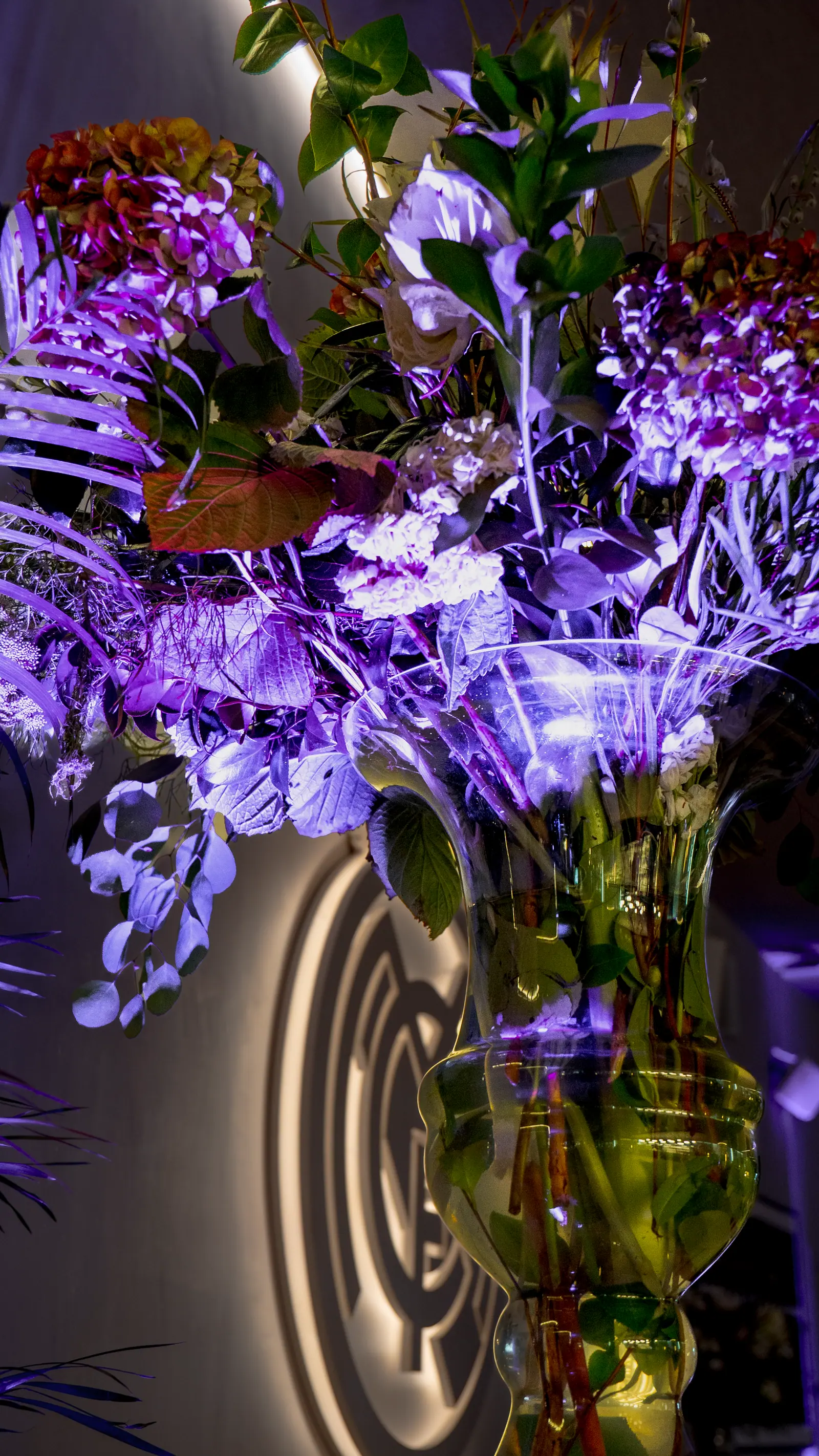 Composición floral púrpura con iluminación LED azul, elemento decorativo de diseño de evento.