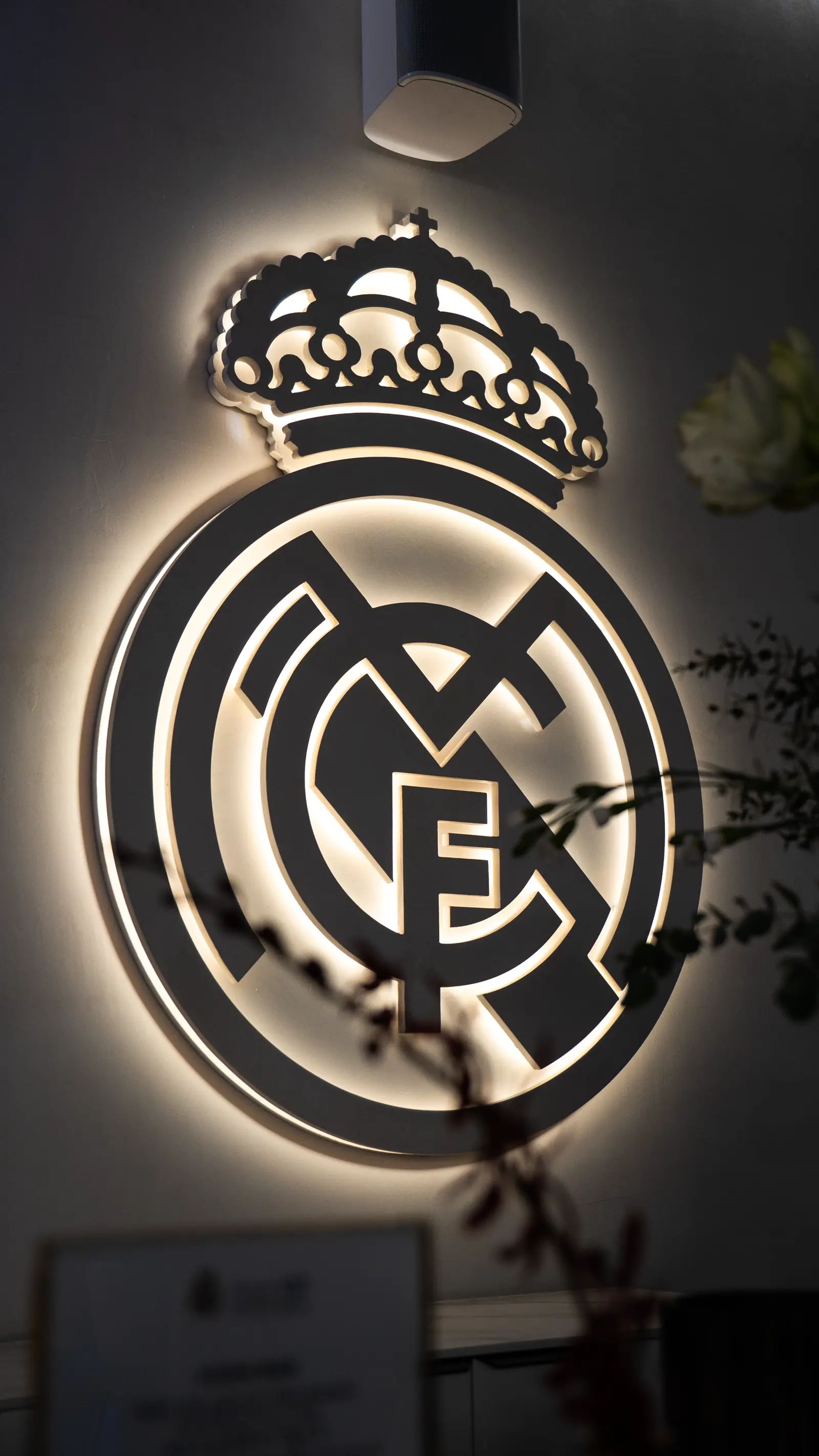 Logotipo Real Madrid en neon blanco sobre fondo oscuro, elemento gráfico de diseño corporativo.